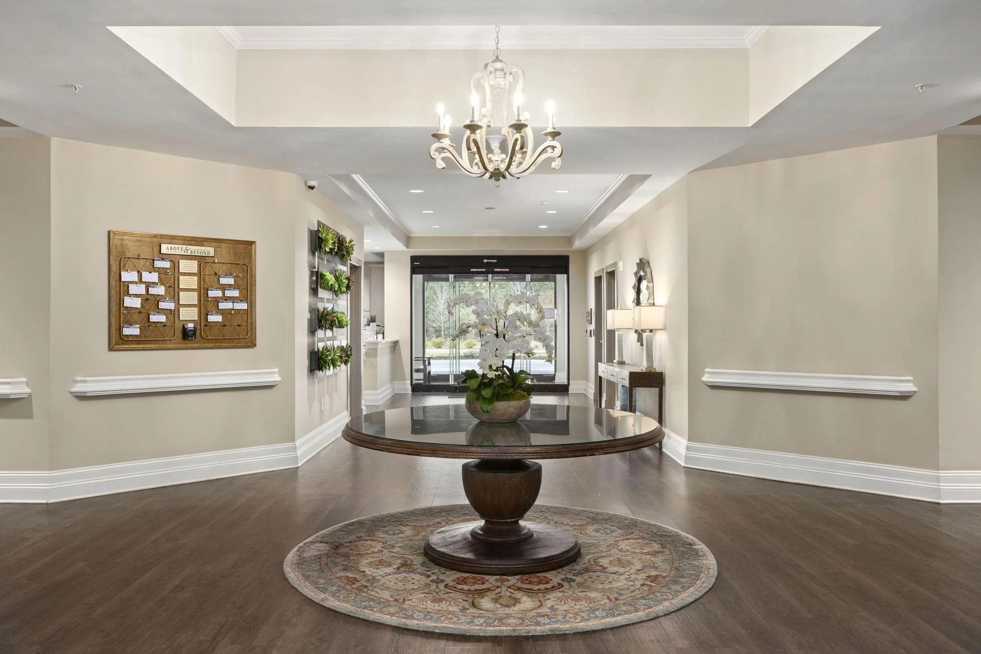 Entrance foyer at a Brickmont community, with a round table and orchid beneath a chandelier